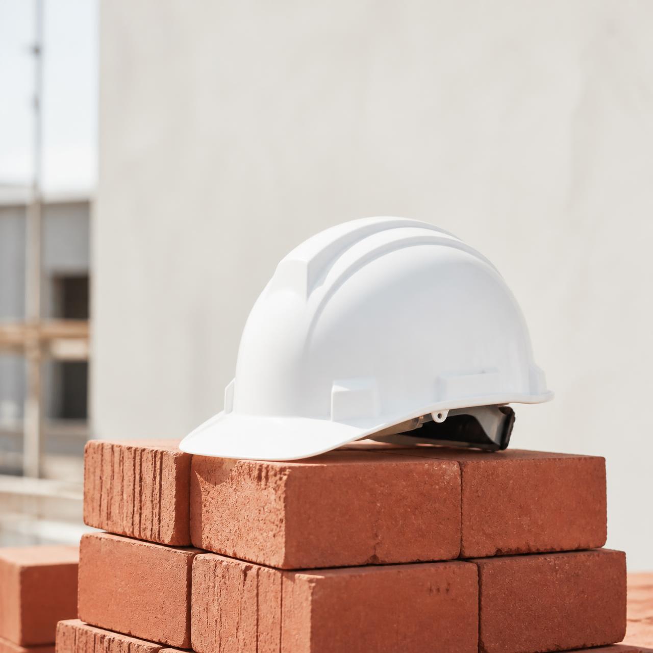 Casco de obra blanco sobre pila de ladrillos